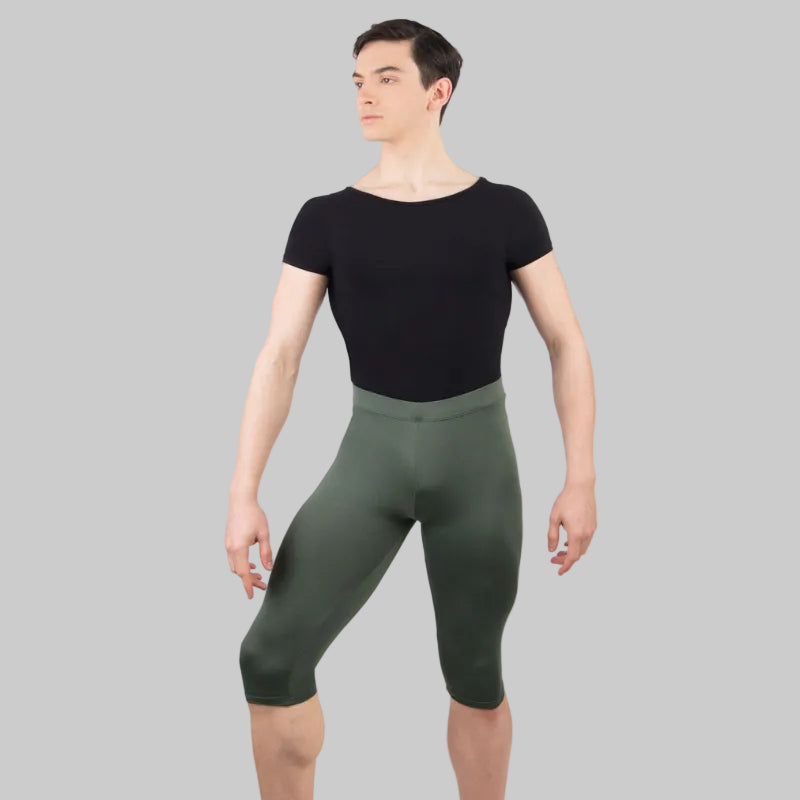 A male model wearing a black scoop neck dance shirt with short sleeves and an attached dance belt.